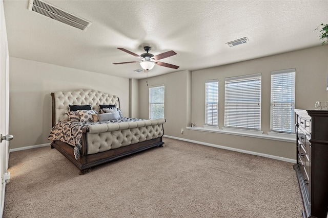 bedroom featuring ceiling fan, light colored carpet, and a textured ceiling