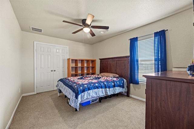 bedroom featuring ceiling fan, light colored carpet, a textured ceiling, and a closet