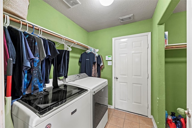 washroom featuring light tile patterned floors, washer and dryer, and a textured ceiling