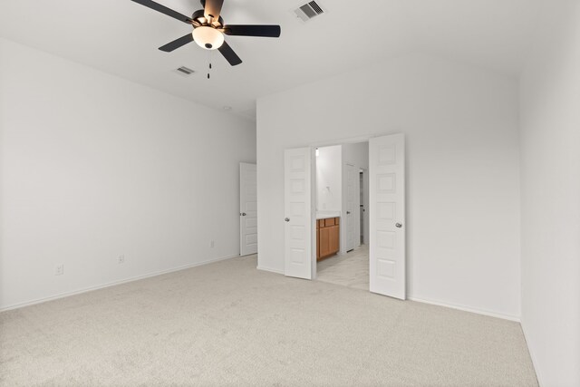 unfurnished bedroom with ceiling fan, ensuite bathroom, and light carpet