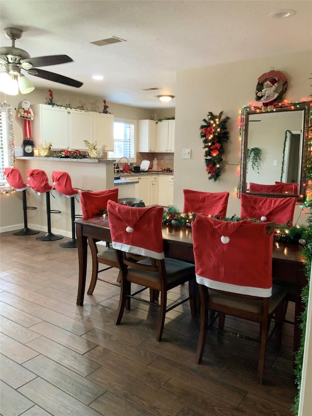 dining area featuring hardwood / wood-style floors, ceiling fan, and sink