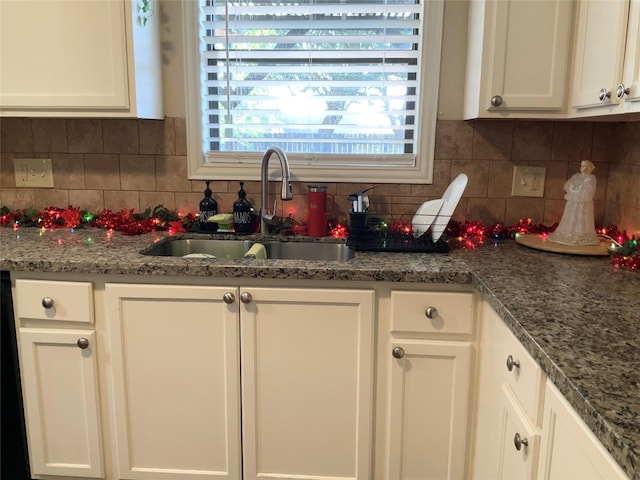 kitchen featuring white cabinets, dark stone countertops, sink, and tasteful backsplash