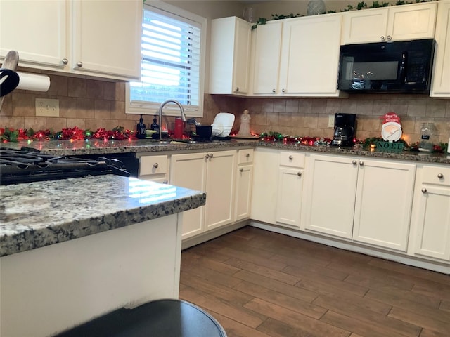 kitchen with white cabinets, dark hardwood / wood-style flooring, dark stone counters, and sink