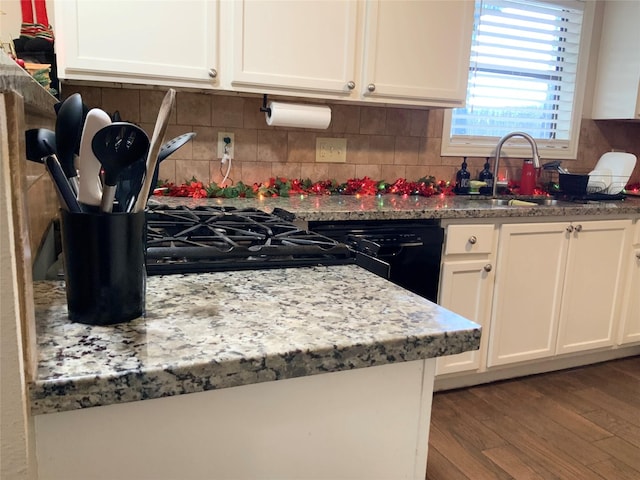 kitchen featuring hardwood / wood-style floors, dishwasher, sink, tasteful backsplash, and white cabinetry