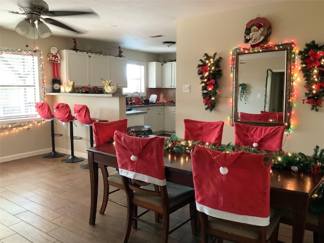 dining space with ceiling fan, light hardwood / wood-style floors, and sink