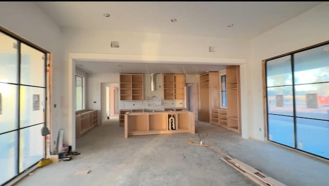 kitchen with light brown cabinetry, concrete floors, and a healthy amount of sunlight