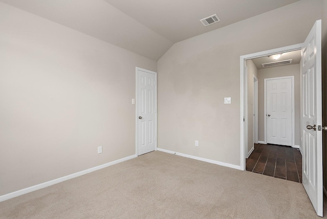 carpeted spare room featuring vaulted ceiling