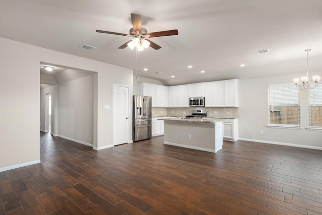 kitchen with white cabinets, light stone countertops, stainless steel appliances, and hanging light fixtures