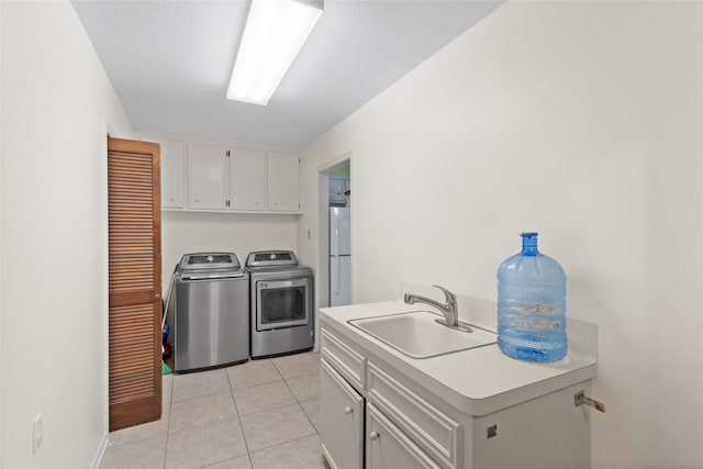 laundry area featuring washer and clothes dryer, light tile patterned floors, cabinets, and sink