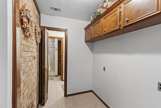 washroom with light tile patterned floors, cabinets, a textured ceiling, and hookup for an electric dryer