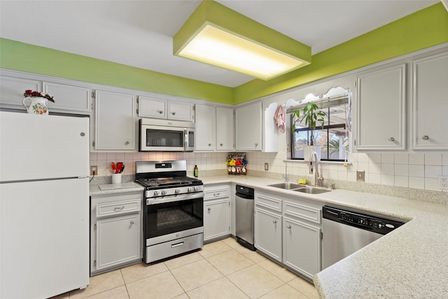 kitchen with backsplash, light tile patterned floors, sink, and appliances with stainless steel finishes