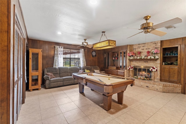 game room featuring a brick fireplace, ceiling fan, light tile patterned floors, billiards, and wood walls