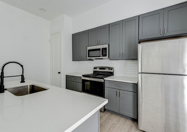 kitchen with light hardwood / wood-style flooring, stainless steel appliances, gray cabinets, and sink