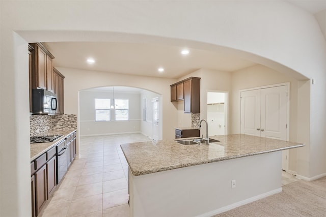 kitchen featuring stainless steel gas stovetop, sink, light stone countertops, tasteful backsplash, and light tile patterned flooring