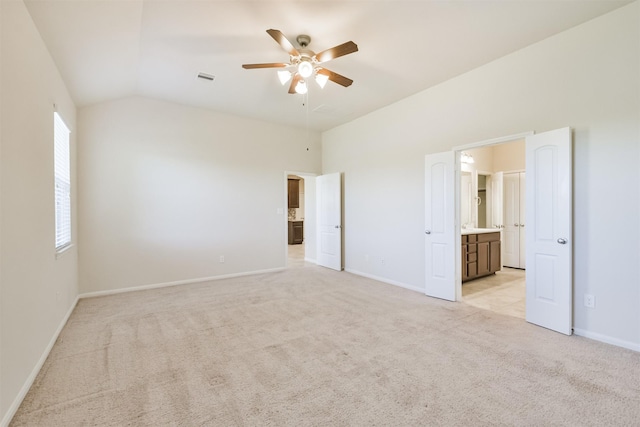 unfurnished bedroom with ceiling fan, light colored carpet, ensuite bathroom, and vaulted ceiling