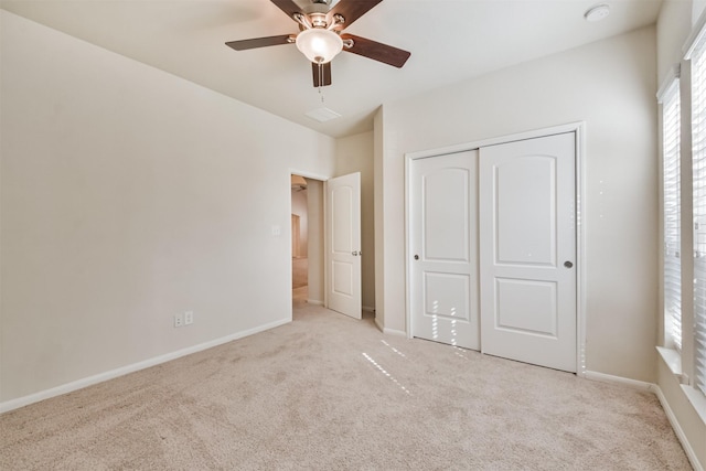 unfurnished bedroom featuring ceiling fan, a closet, and light carpet