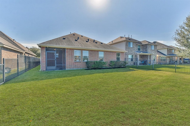 back of house featuring a sunroom and a lawn