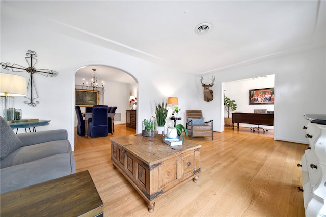 living room featuring ceiling fan with notable chandelier and light hardwood / wood-style flooring