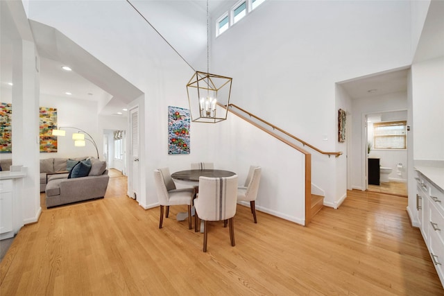 dining space with a notable chandelier, a high ceiling, and light hardwood / wood-style flooring