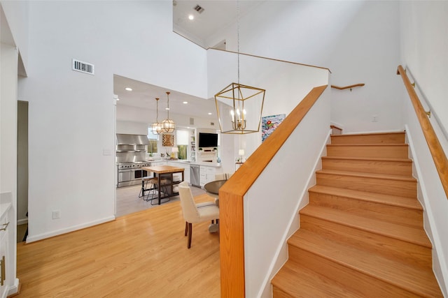 staircase featuring hardwood / wood-style floors, a chandelier, and a high ceiling