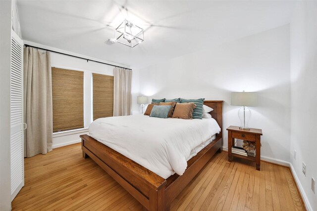 bedroom with light hardwood / wood-style floors and a notable chandelier