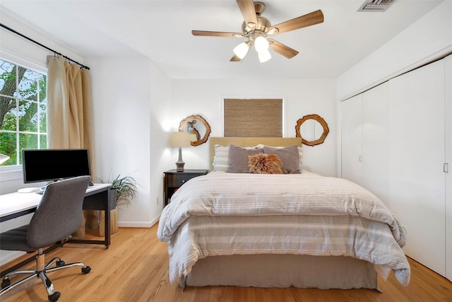 bedroom with multiple windows, ceiling fan, a closet, and light hardwood / wood-style flooring