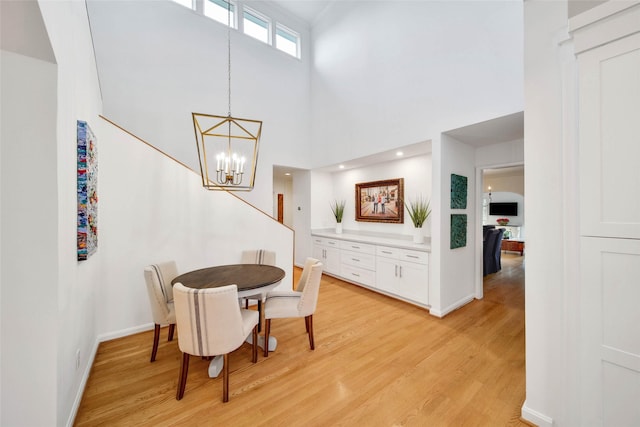 dining space featuring a high ceiling, an inviting chandelier, and light hardwood / wood-style flooring