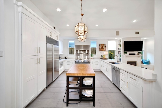 kitchen featuring sink, light tile patterned floors, pendant lighting, white cabinets, and high end appliances