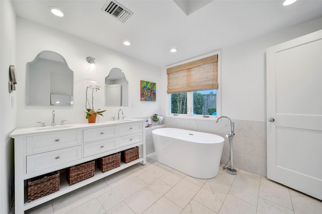 bathroom with a bathing tub, vanity, and tile walls