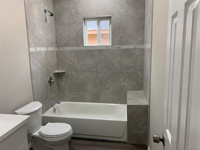 full bathroom with tiled shower / bath, vanity, and toilet