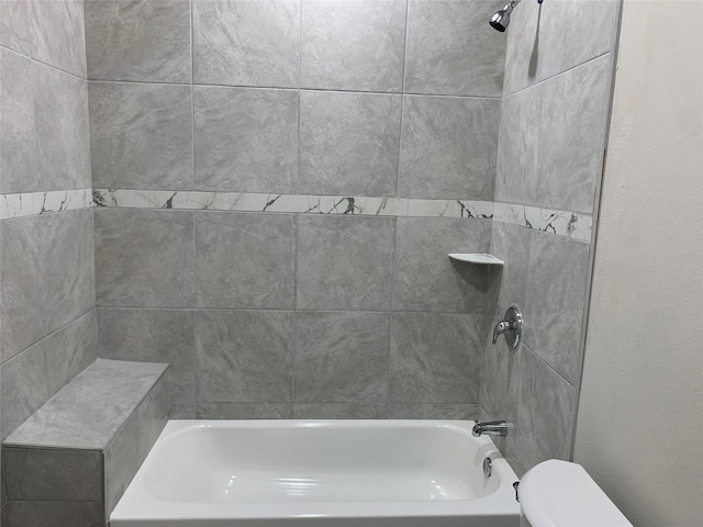 bathroom with toilet and tiled shower / bath