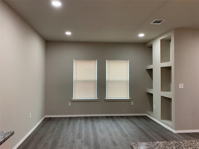 empty room with dark hardwood / wood-style floors and built in features