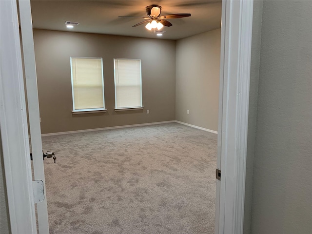 empty room with ceiling fan and light carpet