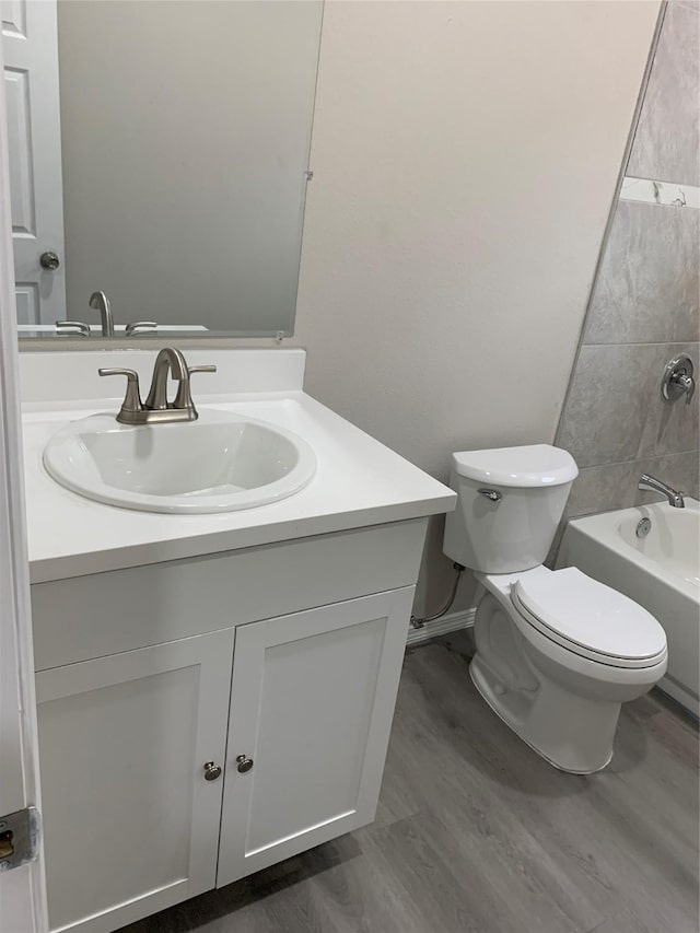 full bathroom featuring hardwood / wood-style floors, vanity, toilet, and tiled shower / bath combo