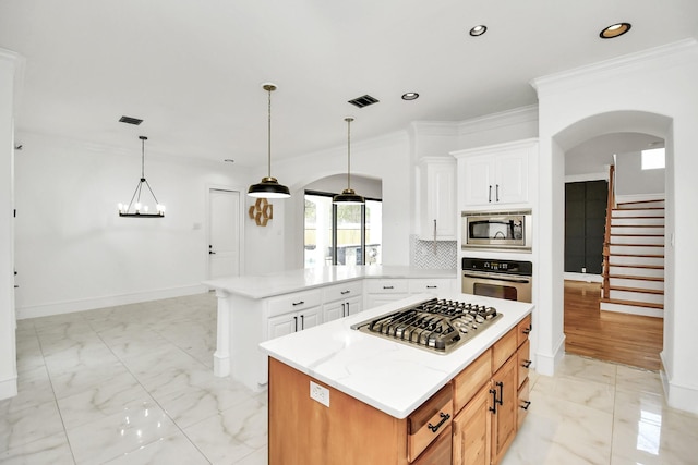 kitchen featuring light stone countertops, white cabinetry, a center island, stainless steel appliances, and crown molding