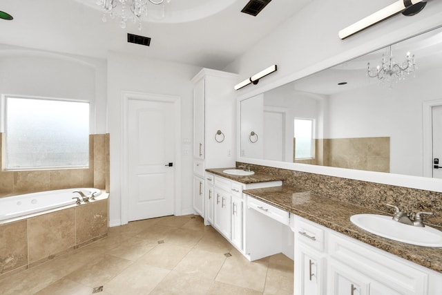 bathroom with tile patterned floors, tiled tub, vanity, and a notable chandelier