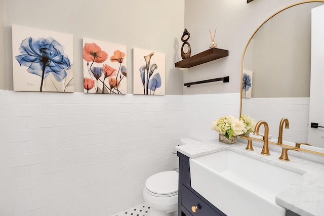 bathroom with vanity, toilet, and tile walls