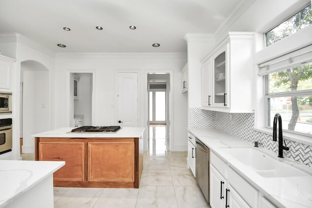 kitchen with white cabinetry, a center island, sink, stainless steel appliances, and light stone counters