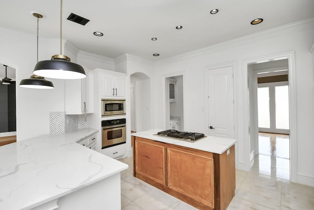 kitchen with light stone counters, backsplash, pendant lighting, white cabinets, and appliances with stainless steel finishes