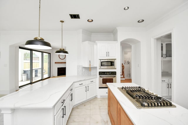 kitchen with kitchen peninsula, appliances with stainless steel finishes, light stone countertops, white cabinets, and hanging light fixtures