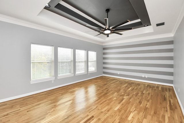 unfurnished room featuring a tray ceiling, crown molding, plenty of natural light, and light hardwood / wood-style floors