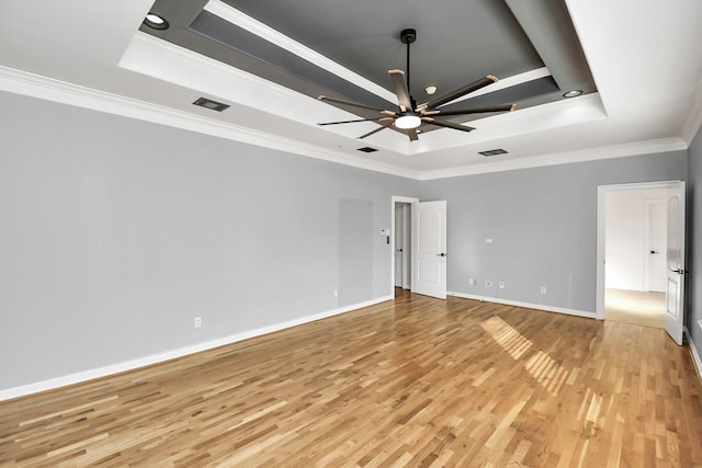 empty room with ceiling fan, light wood-type flooring, crown molding, and a tray ceiling