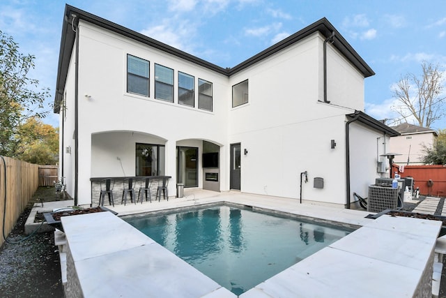 rear view of house with a fenced in pool, an outdoor bar, central AC unit, and a patio