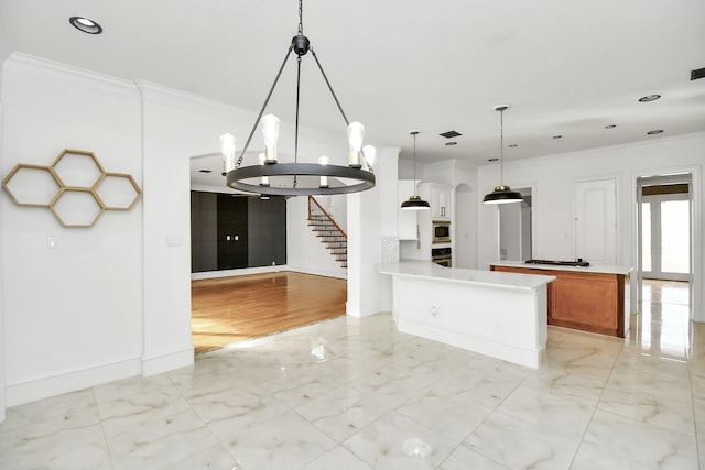 kitchen featuring a notable chandelier, crown molding, decorative light fixtures, white cabinets, and appliances with stainless steel finishes