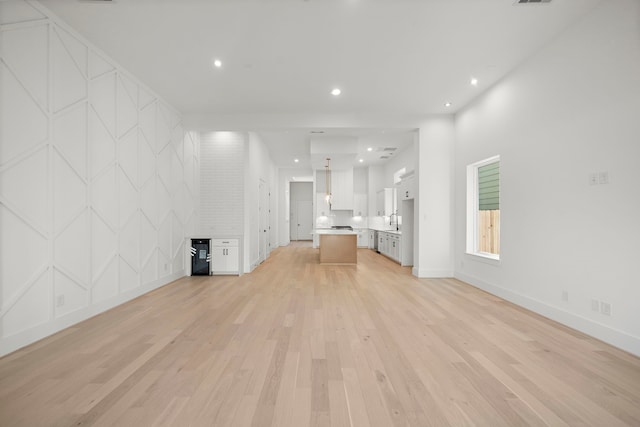 unfurnished living room featuring sink and light hardwood / wood-style floors