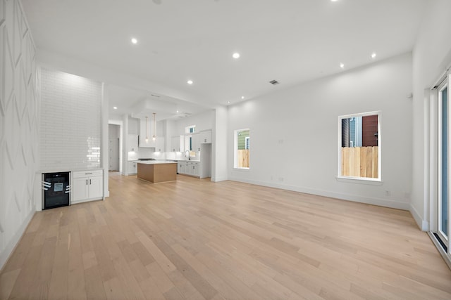 unfurnished living room with a large fireplace, light wood-type flooring, and sink