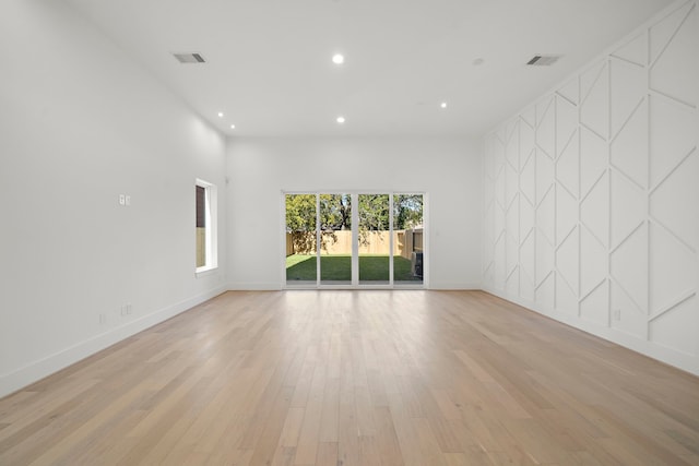 spare room with a towering ceiling and light hardwood / wood-style flooring