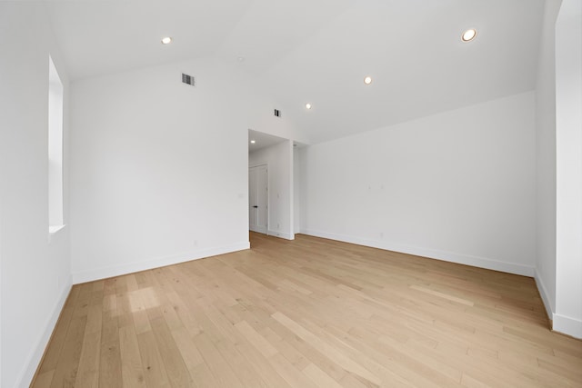 empty room with light wood-type flooring and vaulted ceiling