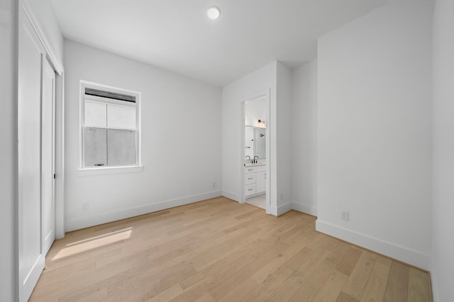 unfurnished bedroom with a closet, ensuite bathroom, light hardwood / wood-style flooring, and sink