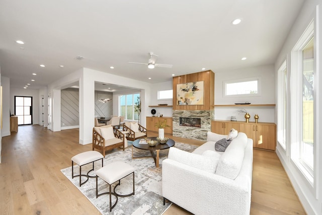 living room with a fireplace, light wood-type flooring, and ceiling fan